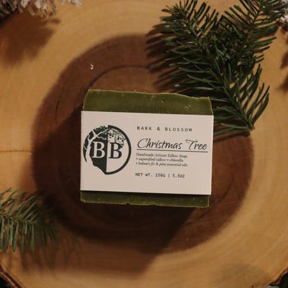 Bar of soap with a label on a wooden log surrounded by greenery