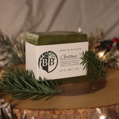 Bar of soap with 'BB' branding on a wooden surface with Christmas decorations.