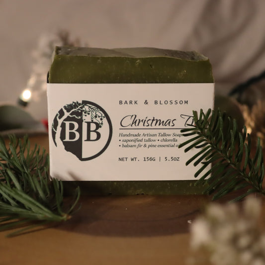 Bar of soap with 'Bark & Blossom' branding on a wooden surface with decorative elements.